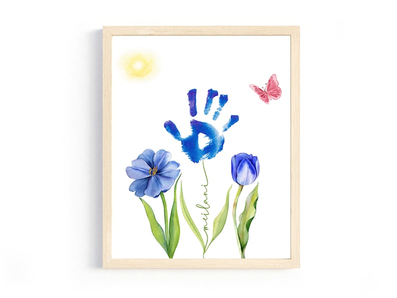 May include: A framed watercolor painting of a blue handprint with a blue flower and a purple tulip. The handprint is surrounded by green leaves and the name "milani" is written in cursive on the stem. A pink butterfly is flying above the flowers.