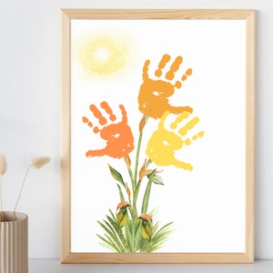 May include: A framed print of a handprint art project depicting three flowers with orange, yellow, and green leaves. The flowers are made from handprints and the background is white.