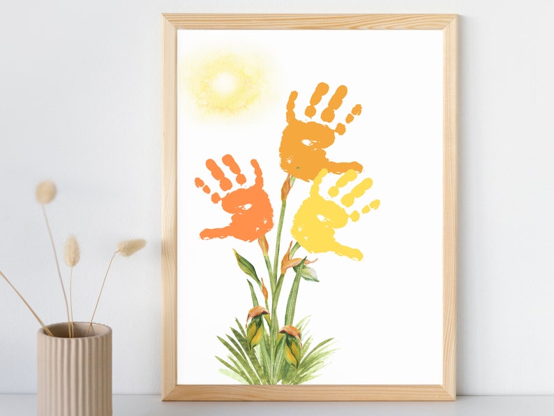 May include: A framed print of a handprint art project depicting three flowers with orange, yellow, and green leaves. The flowers are made from handprints and the background is white.
