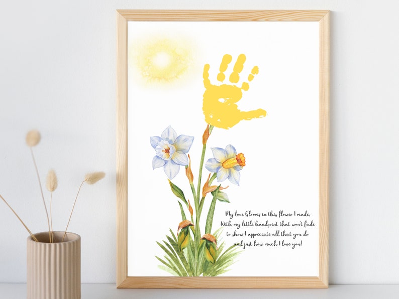 May include: A yellow handprint is used to create the stem of a watercolor painting of a daffodil flower. The text reads: "My love blooms in this flower I made, with my little handprint that won't fade to show I appreciate all that you do and just how much I love you!"