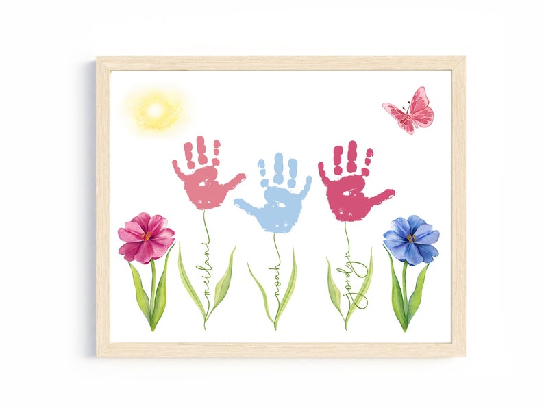 May include: A framed print with three handprints in pink, blue, and pink, each with a flower and name below:  'milani', 'noah', and 'jordyn'. A butterfly is in the upper right corner and a yellow sun is in the upper left corner.
