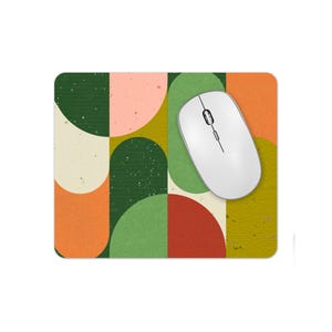 May include: A mouse mat with a geometric design featuring green, orange and yellow circles and semi-circles. The mouse mat is on a white background.