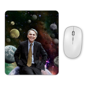 May include: A smiling man in a suit and tie sits on a planet in a space scene with stars and planets in the background.