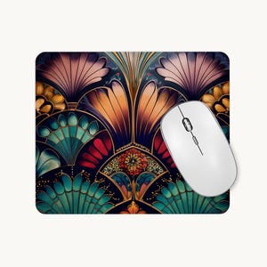 May include: A rectangular mouse mat featuring a symmetrical, fan-shaped pattern in shades of teal, orange, pink, and gold against a dark background, with a white wireless computer mouse resting on the right side of the surface.