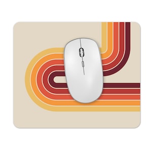 May include: A retro-style mouse mat with a design of curved, multi-coloured stripes in shades of orange, yellow, and brown. The mouse mat is beige and has a white computer mouse on top.