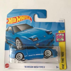 May include: A blue Hot Wheels die-cast toy car of a '96 Nissan 180SX Type X. The car is on a blue and white card with the Hot Wheels logo and 'HW: The '90s' text. The car has white wheels and a white stripe.