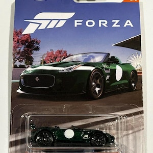 以下が含まれることがあります： 緑色の'15 Jaguar F-Type Project 7のHot Wheelsダイキャストカー。Forzaシリーズの一部です。パッケージにはHot Wheelsのロゴ、Forzaのロゴ、レーストラック上の車の写真が掲載されています。車体側面には白い円があります。