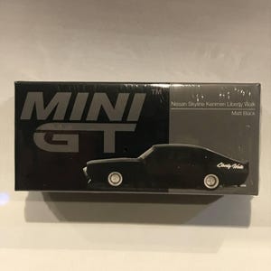 以下が含まれることがあります： 黒と銀の箱に白い文字で「MINI GT」と書かれています。箱には、白い文字で「Liberty Walk」と書かれた黒い日産スカイラインケンメリリバティーウォークが描かれています。箱には「Nissan Skyline Kenmeri Liberty Walk Matt Black」という文字が印刷されています。