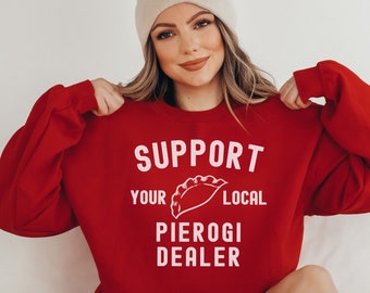 May include: Red sweatshirt with the text "Support Your Local Pierogi Dealer" in white letters. A white pierogi is pictured above the text.