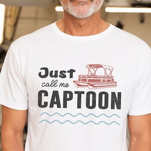 May include: White t-shirt with a graphic of a pontoon boat and the text "Just call me CAPTOON".