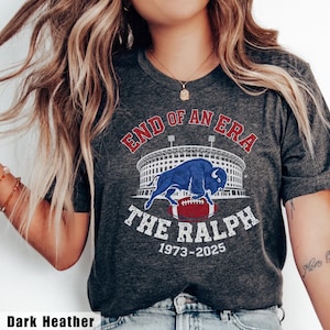 May include: Dark heather gray t-shirt with a graphic that reads "END OF AN ERA" above a stadium image and a blue buffalo over a football. The text "THE RALPH 1973-2025" is below the football.