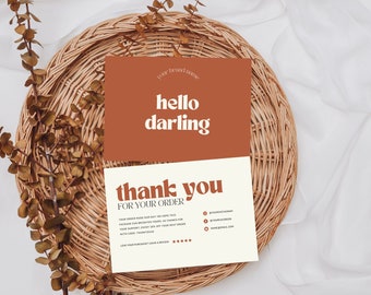 Op de afbeelding: Een bedankkaart met de tekst "hello darling" op een bruine achtergrond en "thank you for your order" op een crème achtergrond. De kaart ligt op een gevlochten mand.