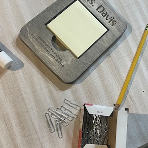 May include: A wooden sign with the text "Ms. Davis" and a space for a sticky note. The sign has the text "Thank you for sticking by me when times were difficult".