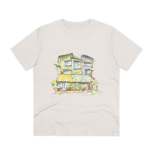 May include: A white t-shirt featuring a watercolour illustration of a multi-coloured building with a yellow awning. The building has a green roof and windows. The illustration is in a sketchy style.