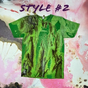 May include: Green t-shirt with a tie-dye pattern in shades of green and brown. The shirt has a crew neck and short sleeves. "Style #2" is written in purple at the top of the image.
