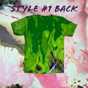 May include: Green tie-dye t-shirt with a splatter pattern. The back of the shirt is shown. The shirt has a crew neck and short sleeves. "STYLE #1 BACK" is written in purple text at the top of the image.
