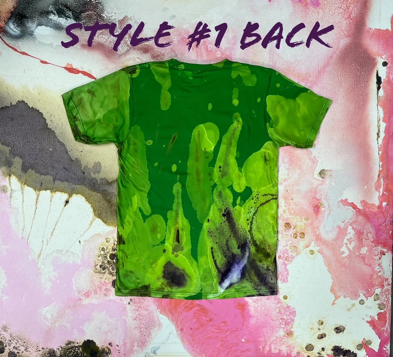 May include: Green tie-dye t-shirt with a splatter pattern. The back of the shirt is shown. The shirt has a crew neck and short sleeves. "STYLE #1 BACK" is written in purple text at the top of the image.
