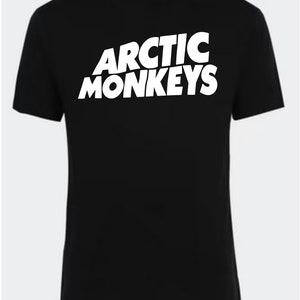 May include: Black t-shirt with a white "Arctic Monkeys" logo printed on the front.