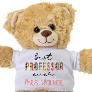 May include: A brown teddy bear wearing a white t-shirt with the text "best PROFESSOR ever" and "MRS. WALKER" in pink letters.