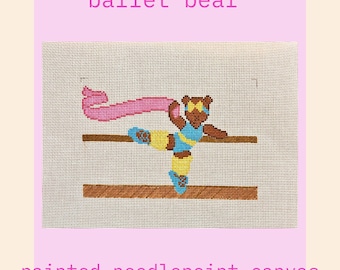 May include: A painted needlepoint canvas featuring a brown bear in a ballet pose. The bear wears a blue and yellow leotard, blue ballet shoes, and a pink scarf. The text "ballet bear" and "painted needlepoint canvas" are displayed.