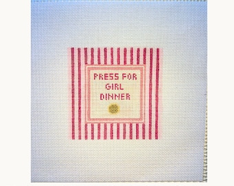 May include: Painted needlepoint canvas with the text "Emergency Girl Dinner". The canvas features a central square with the words "Press for Girl Dinner" in a pink frame, surrounded by pink and white stripes.