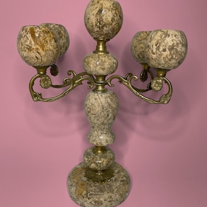 Peut inclure: Un candélabre à cinq branches doté d'une colonne centrale et de coupelles en pierre beige et brune marbrée. La structure est reliée par des bras en laiton incurvés et ornés, avec des détails floraux aux articulations et une base circulaire.