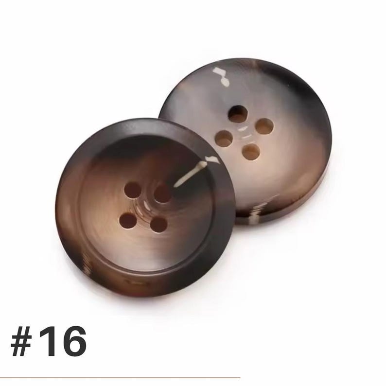 K&ouml;nnte beinhalten: Zwei gro&szlig;e, runde Kn&ouml;pfe mit einem marmorierten braunen und beigen Muster. Jeder Knopf hat vier L&ouml;cher zum Ann&auml;hen. Die Nummer "#16" ist unten im Bild in Schwarz aufgedruckt.
