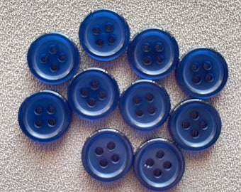 May include: Ten blue plastic buttons with four holes each. The buttons are arranged in a circle on a light gray fabric background.