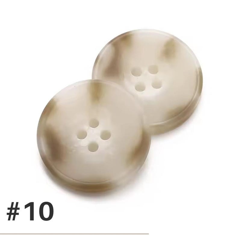 K&ouml;nnte beinhalten: Zwei runde, cremefarbene Kn&ouml;pfe mit jeweils vier L&ouml;chern. Die Kn&ouml;pfe haben ein marmoriertes Aussehen mit braunen und beigen Wirbeln. Die Nummer "#10" ist unten im Bild schwarz gedruckt.