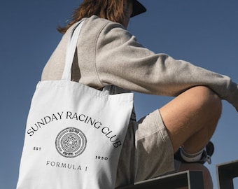 May include: A white tote bag with black text that reads "SUNDAY RACING CLUB EST 1950 FORMULA I" and a black and white graphic of a tire with a sun in the center.