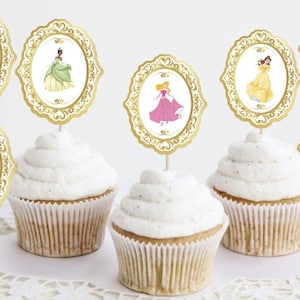 May include: Six cupcake toppers featuring Disney princesses in gold oval frames. The princesses include Ariel, Tiana, Aurora, Belle, Cinderella, and Rapunzel.