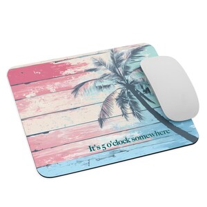 May include: A rectangular mouse mat with a tropical design. It features a palm tree illustration on a background of pastel pink, blue, and white wooden planks. The text "It's 5 o'clock somewhere" is printed on the bottom.