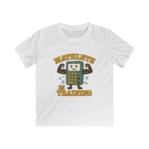 May include: White t-shirt featuring a cartoon calculator character with the text "MATHLETE IN TRAINING". The calculator has a smiling face and flexed arms. The design includes numbers and math symbols.