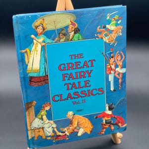 May include: A blue book with the title "The Great Fairy Tale Classics Vol. II" and illustrations of fairy tale characters.