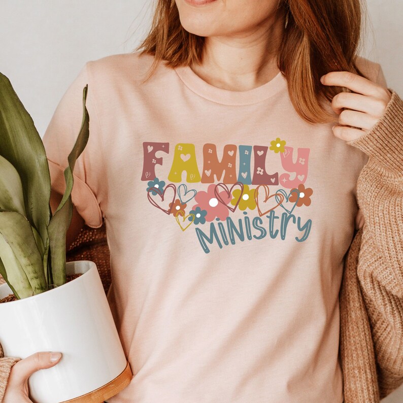 May include: A pink t-shirt with the text "FAMILY MINISTRY" in colorful letters with hearts and flowers around the text.