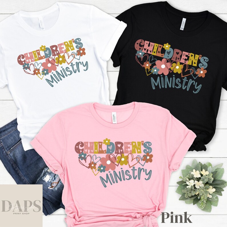 May include: Three t-shirts in white, black, and pink with the text "Children's Ministry" in a colorful, whimsical font surrounded by hearts and flowers.