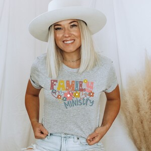May include: A gray t-shirt with the text "FAMILY MINISTRY" in colorful letters with hearts and flowers around the text.