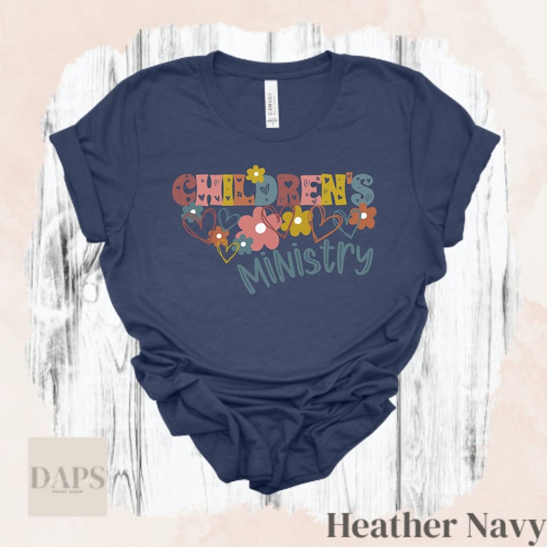 May include: A heather navy blue t-shirt with the text "Children's Ministry" in colorful letters with hearts and flowers around the text.