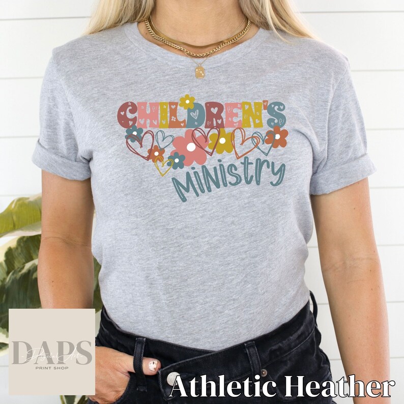 May include: A gray t-shirt with the text "Children's Ministry" in colorful letters surrounded by hearts and flowers.