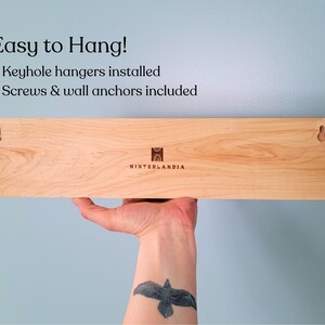 Back of wood jewelry hanger showing two keyhole hangers and the company logo.