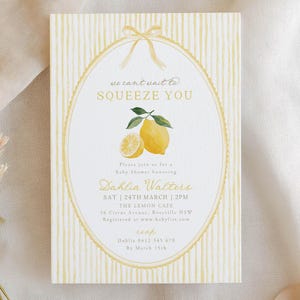 May include: A baby shower invitation with a lemon theme. The invitation has a yellow and white striped background with an oval frame. Inside the frame is a lemon illustration and the text "we can't wait to SQUEEZE YOU".