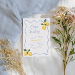 May include: A baby shower invitation with the text "Ciao Baby!" in light blue script. The invitation features watercolor lemons and a blue border. The invitation includes details for Natalia Rose's baby shower.