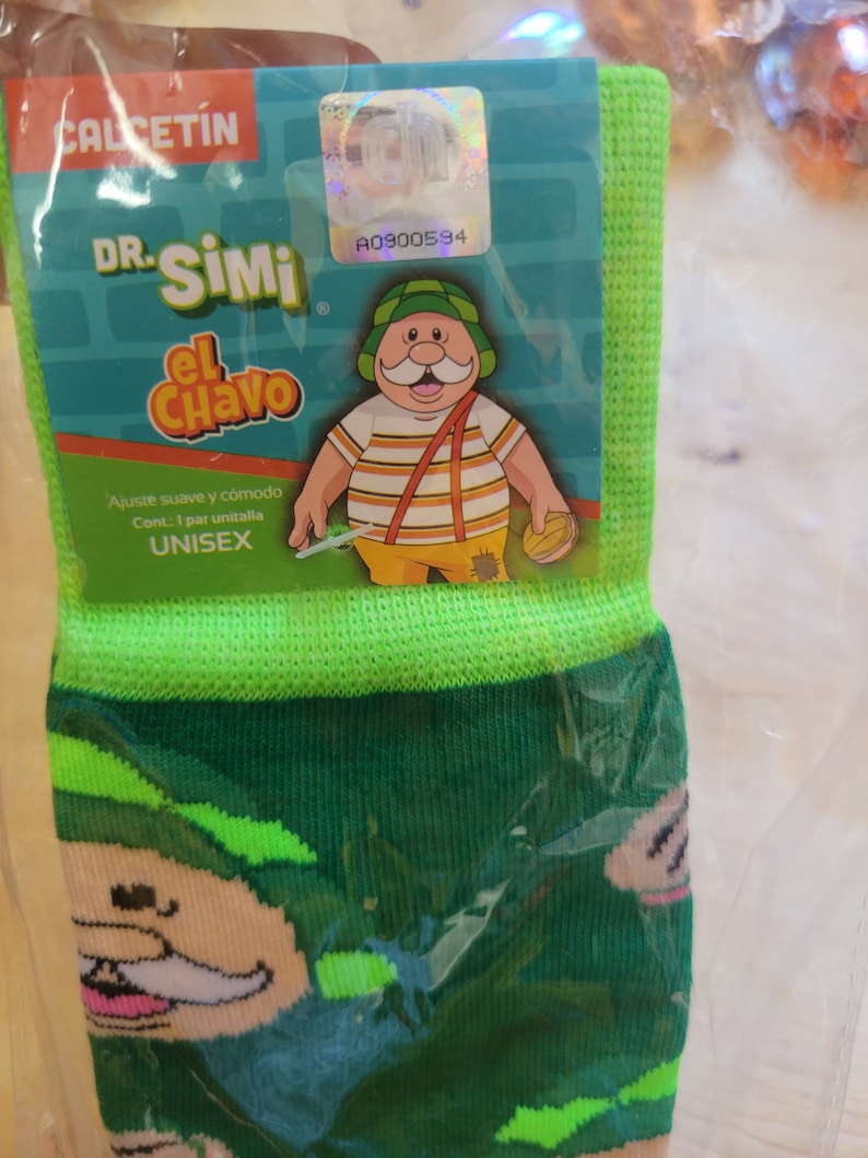 Puede incluir: Calcetines verdes y verde oscuro con un personaje de dibujos animados con sombrero verde y camisa a rayas. El embalaje incluye el texto "CALCETIN" y "DR. SIMI El Chavo". Los calcetines est&aacute;n etiquetados como "UNISEX".