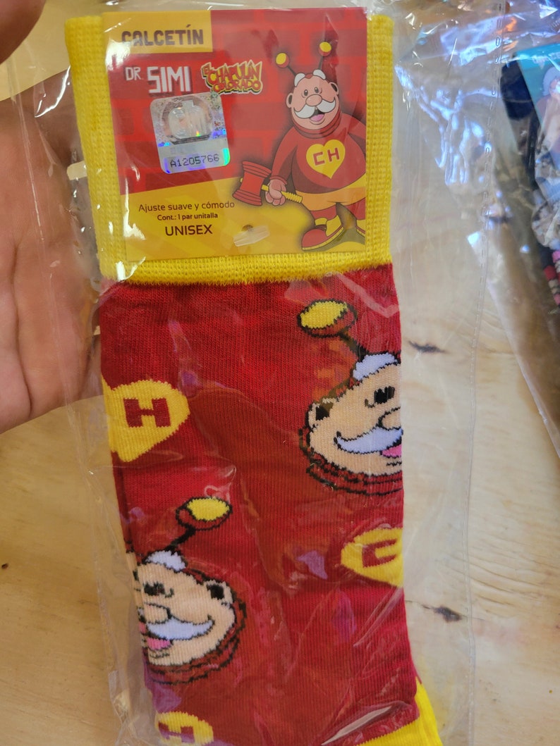 Puede incluir: Calcetines unisex rojos y amarillos con un dise&ntilde;o de personaje de dibujos animados. Empaquetados en una bolsa de pl&aacute;stico transparente. El embalaje incluye el texto "CALCETIN DR SIMI" y "UNISEX".