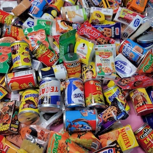 May include: A colorful collection of miniature food and beverage items, including cereal boxes, candy bars, canned goods, and snack bags. The items are arranged in a random pattern, creating a visually appealing and playful display.