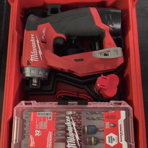 May include: A red Milwaukee FUEL drill and driver set with a 32-piece packout driver bit set in a red and black carrying case.