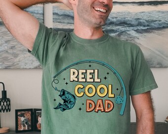 May include: Green t-shirt with a retro-style graphic that says "Reel Cool Dad" with a fishing rod and fish illustration.