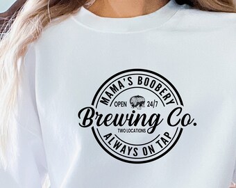 May include: White sweatshirt with a black circular logo that says "Mama's Boobery Brewing Co. Open 24/7 Two Locations Always On Tap"