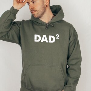 May include: A green hooded sweatshirt with the word "DAD²" printed in white on the front.