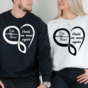 May include: Two black and white sweatshirts with an infinity symbol heart design. The text on the sweatshirts reads "Until we meet again" and "Date Name".